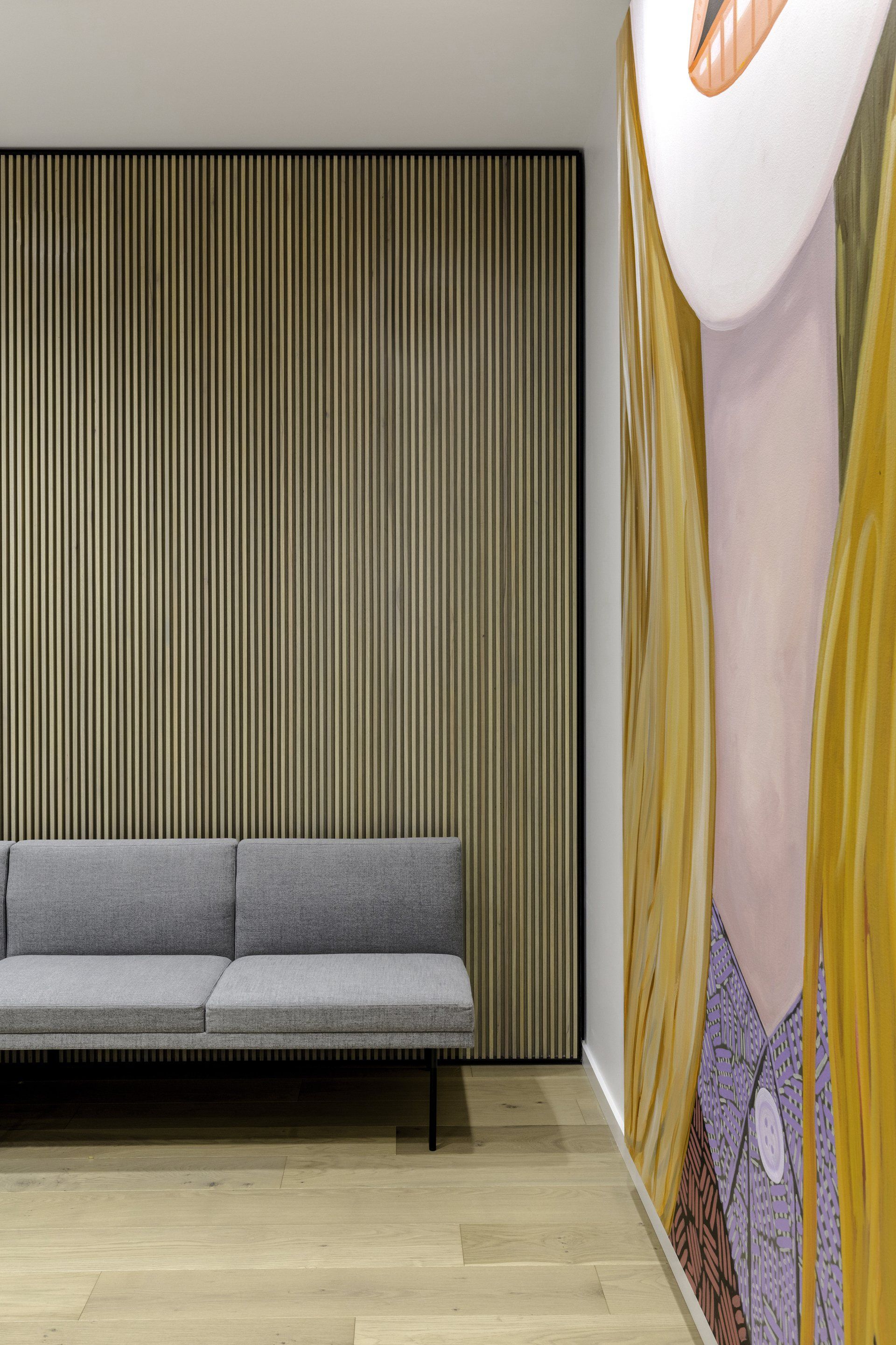 A living room with a couch and a large painting on the wall.