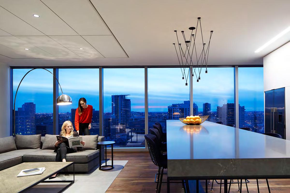 A woman is sitting on a couch in a living room with a view of the city.