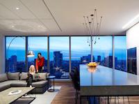 A living room with a lot of windows and a dining table.