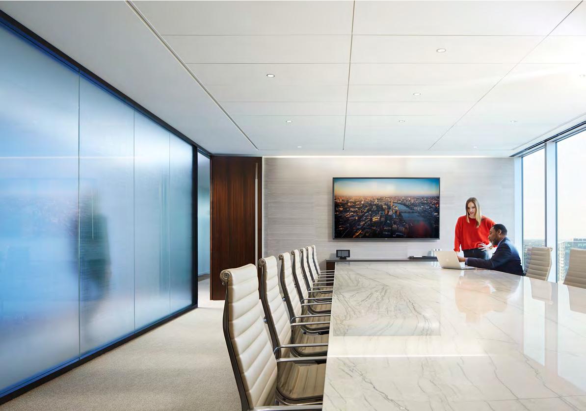Two people are standing in a conference room with a long table and chairs.