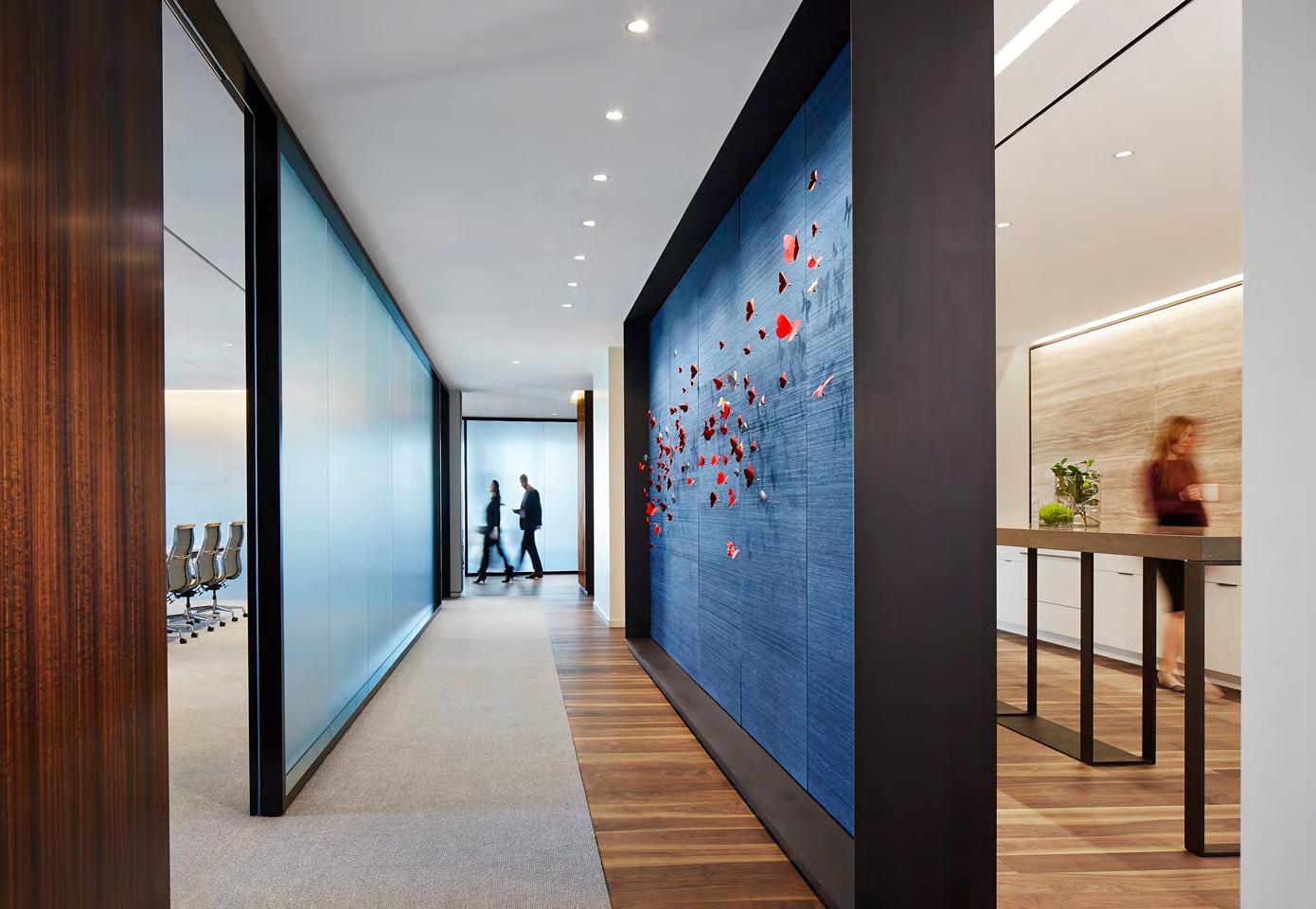 A hallway with a blue wall and people walking down it.