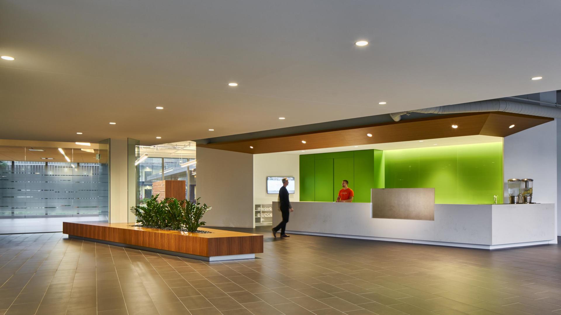 A man in a red shirt is standing at a counter in a lobby.