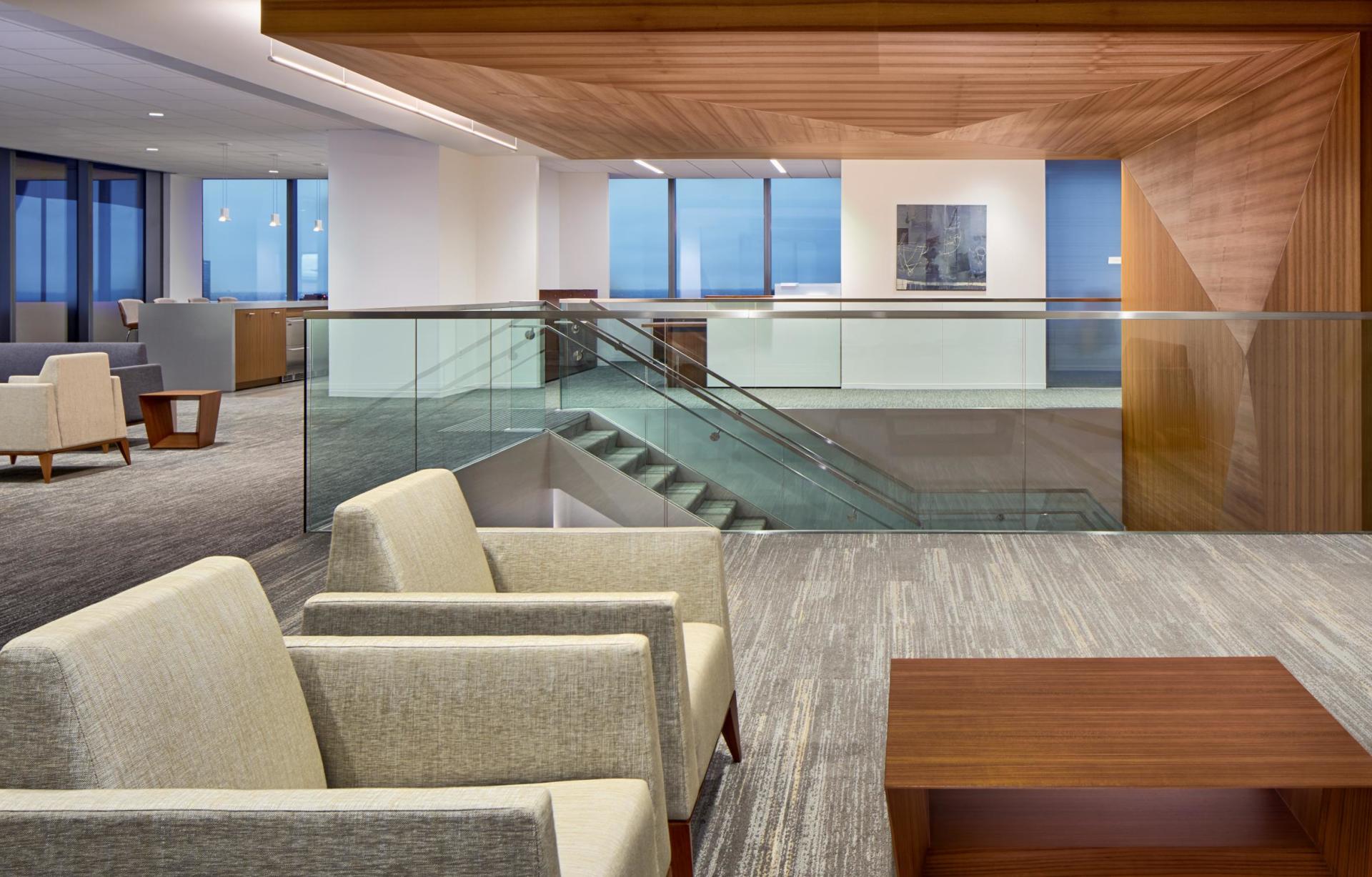 A waiting room with chairs , tables , and stairs.