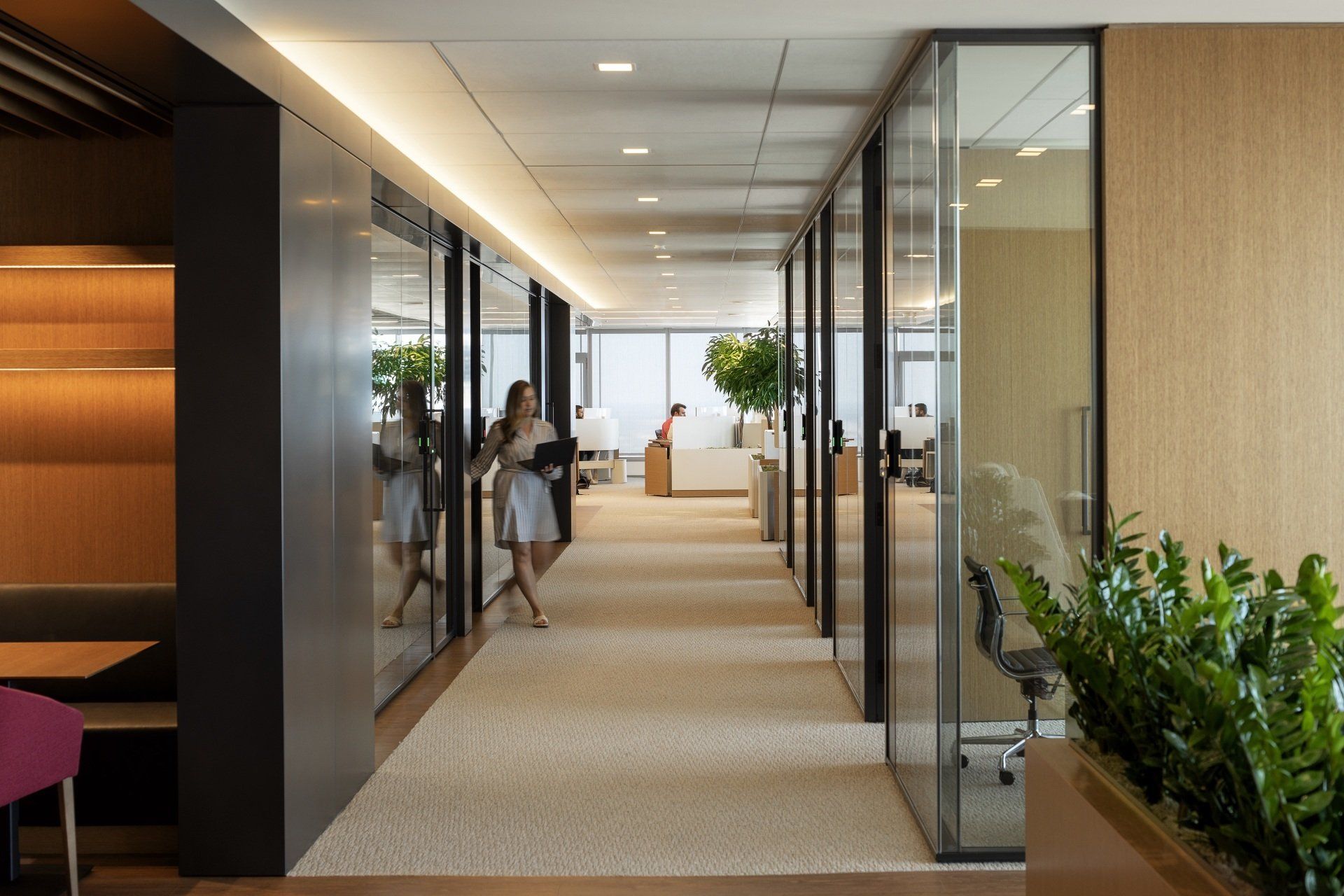 A woman is walking down a hallway in an office building.