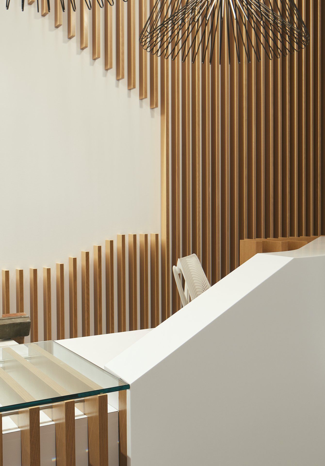 A white desk with a glass top in front of a wooden wall