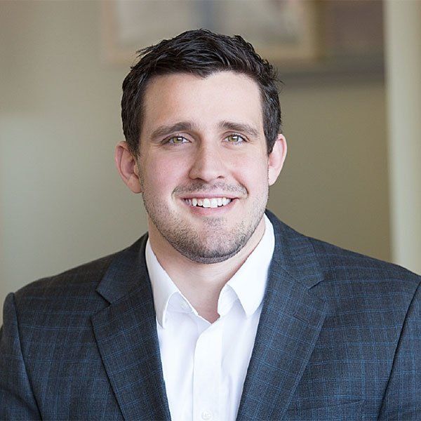 A man in a suit and white shirt is smiling for the camera.