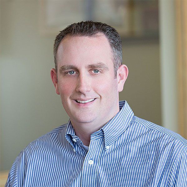 A man in a blue and white striped shirt is smiling for the camera.