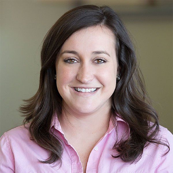 A woman in a pink shirt is smiling for the camera.