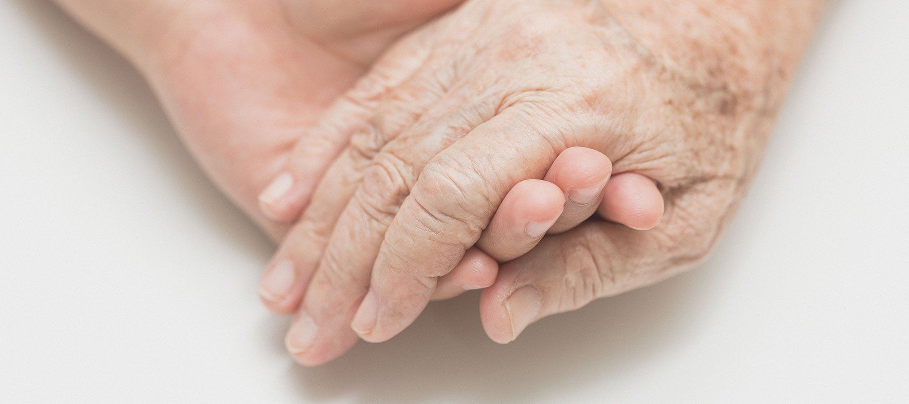 A young woman is hugging an older woman in a wheelchair.