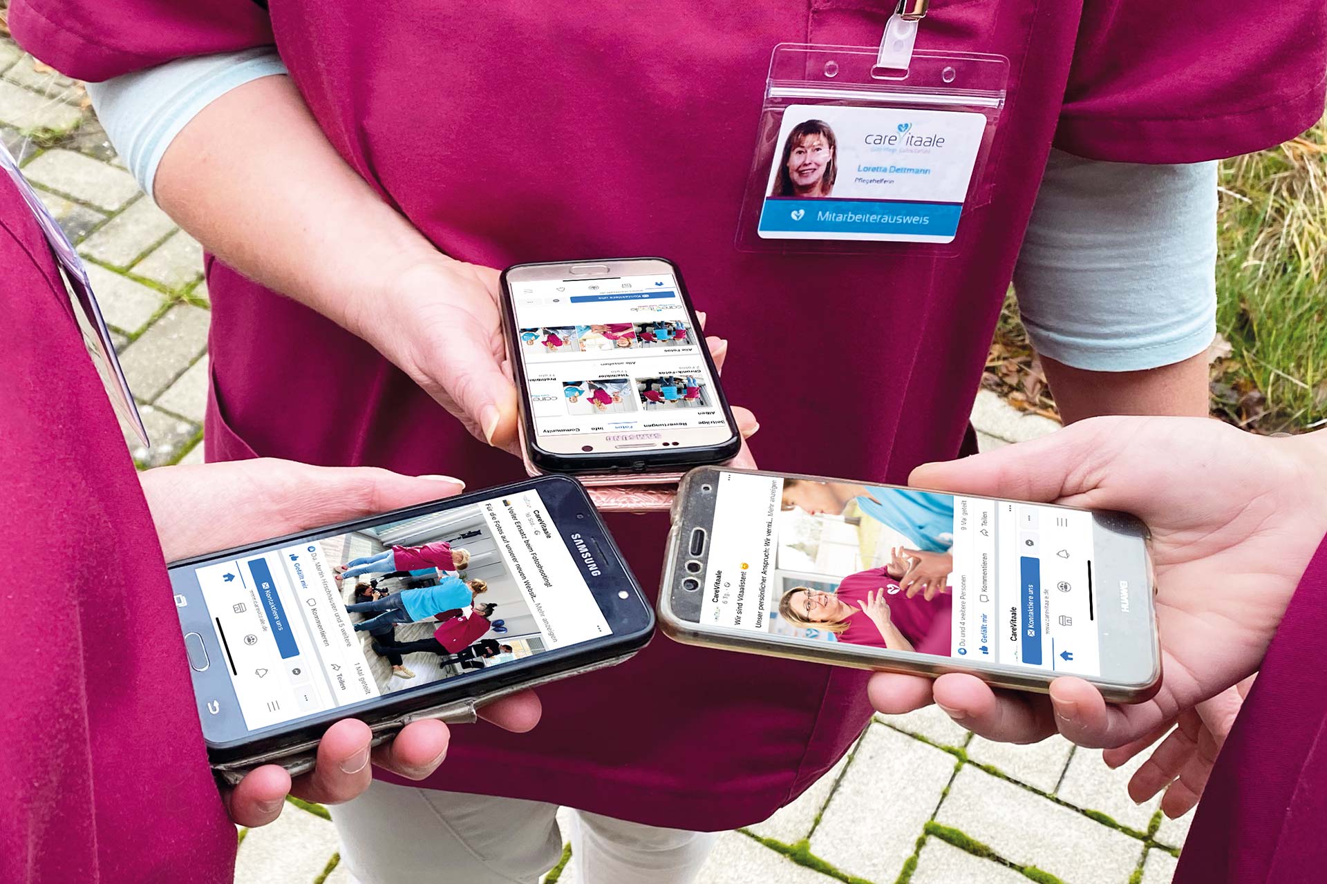 PFLEGERWOHL Facebook Unternehmensseite Drei Mitarbeiterinnen stehen zusammen und haben die Facebook-Seite eines Pflegedienstes an ihrem Smartphone geöffnet