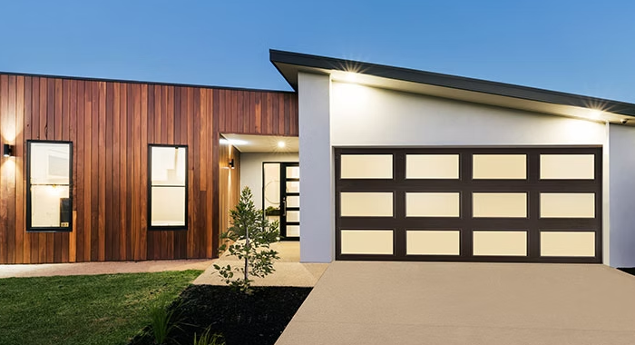 Modern house exterior with wood siding, white trim, and a garage at dusk
