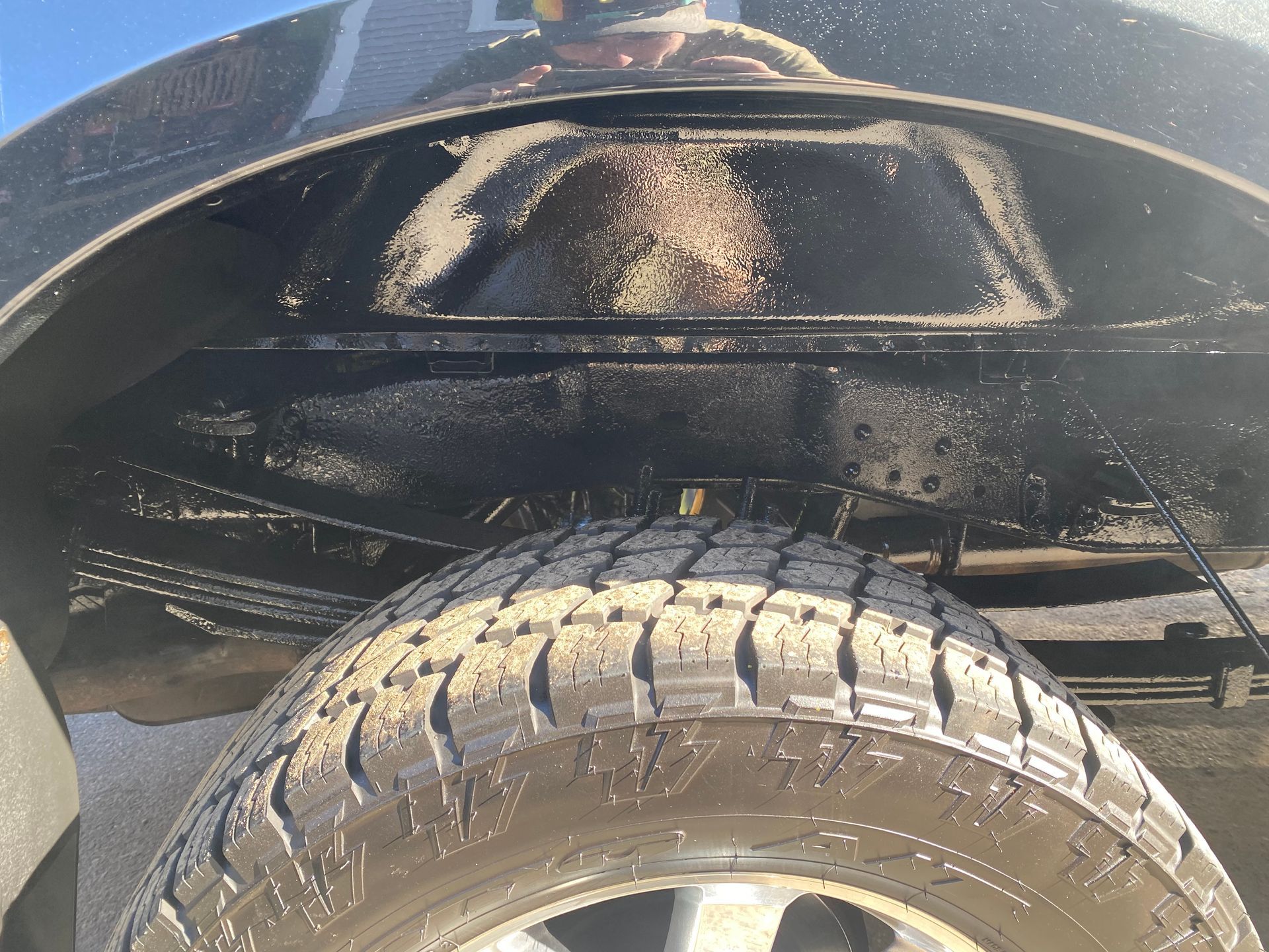 A person is taking a picture of the underside of a truck.