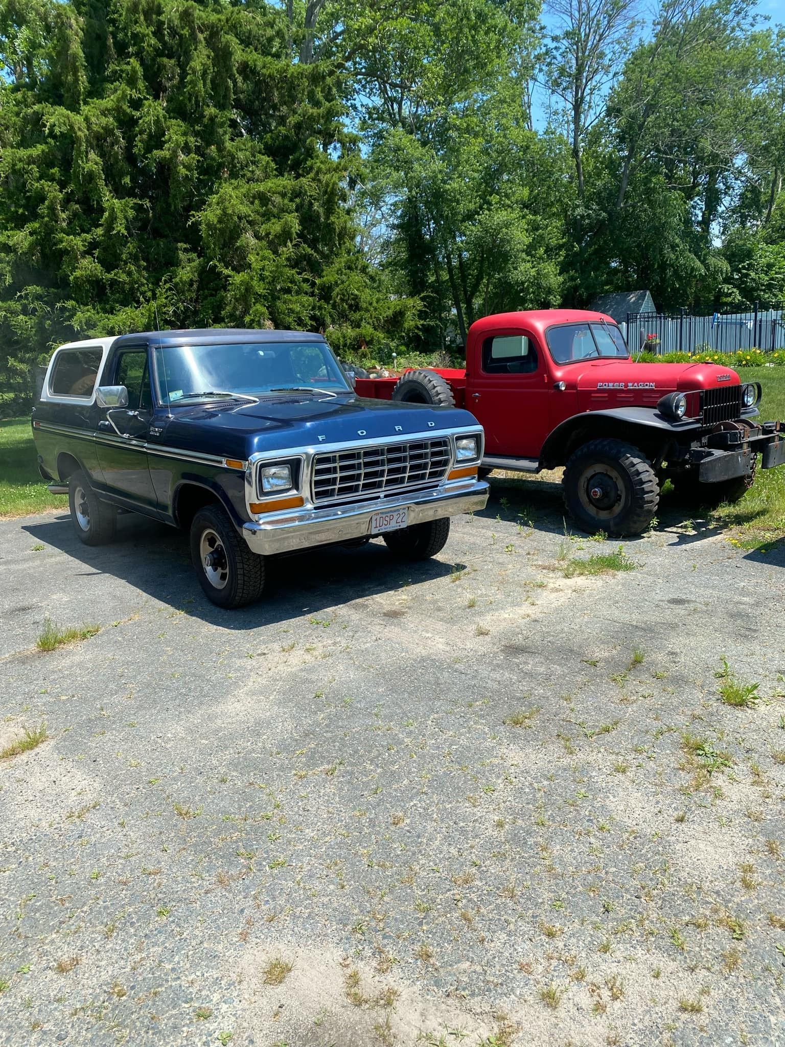 A black truck and a red truck are parked next to each other in a parking lot.