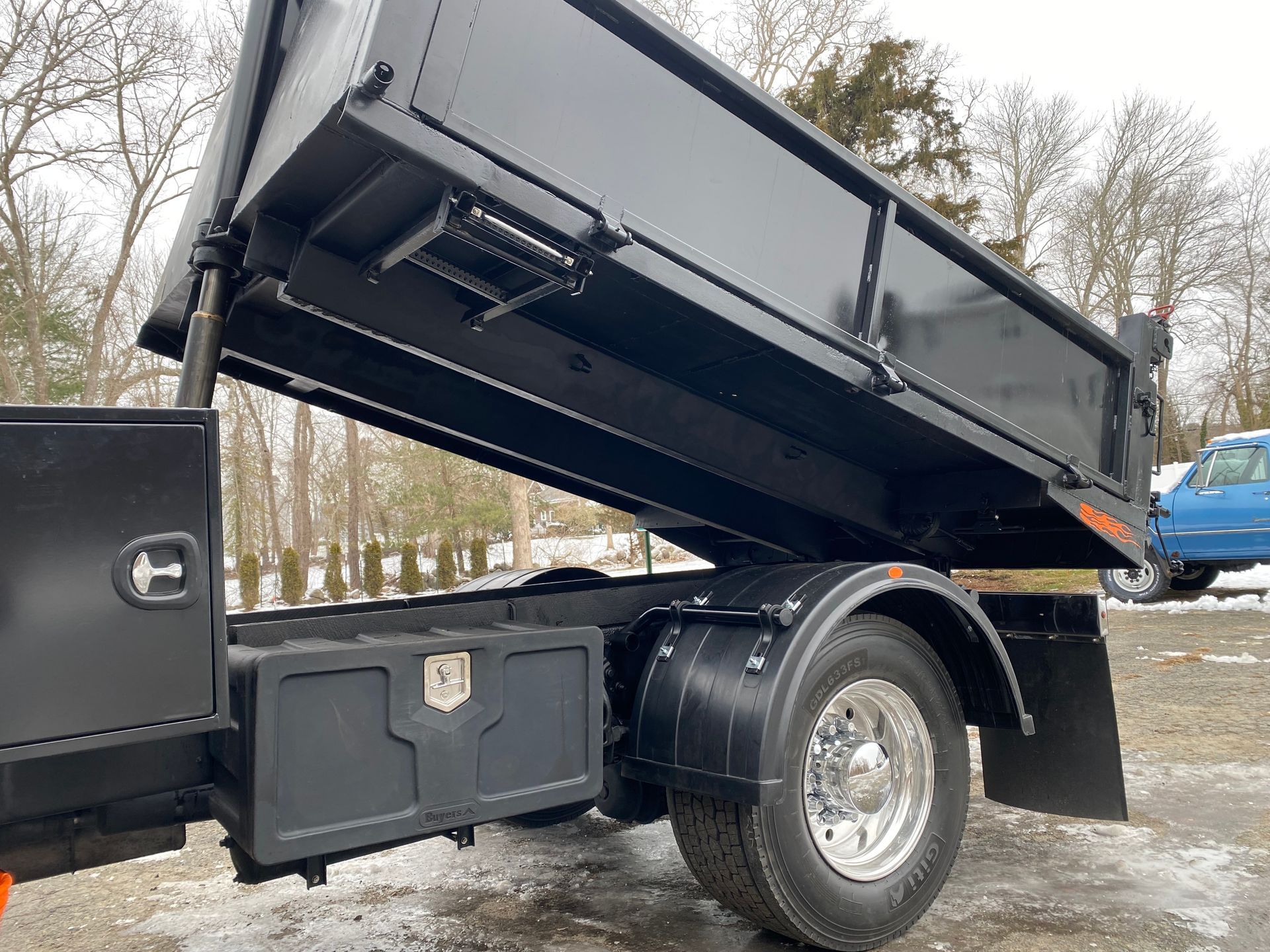 A dump truck with its bed open is parked in a parking lot.
