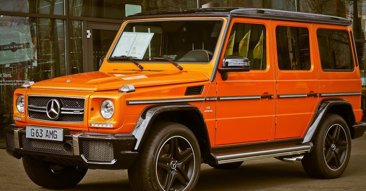 An orange mercedes benz g63 amg is parked in front of a building.