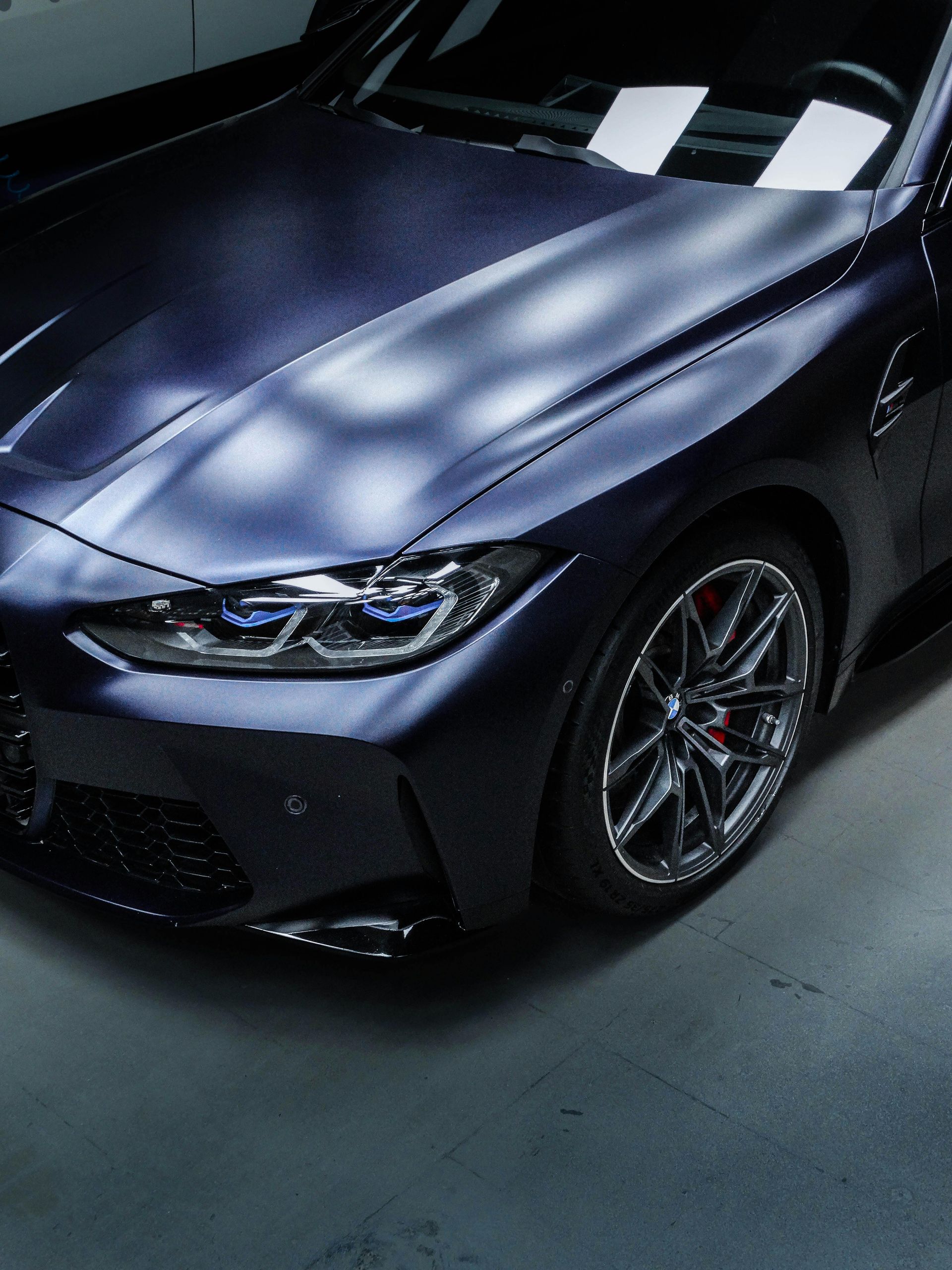 The underside of a car is sitting on a lift in a garage.