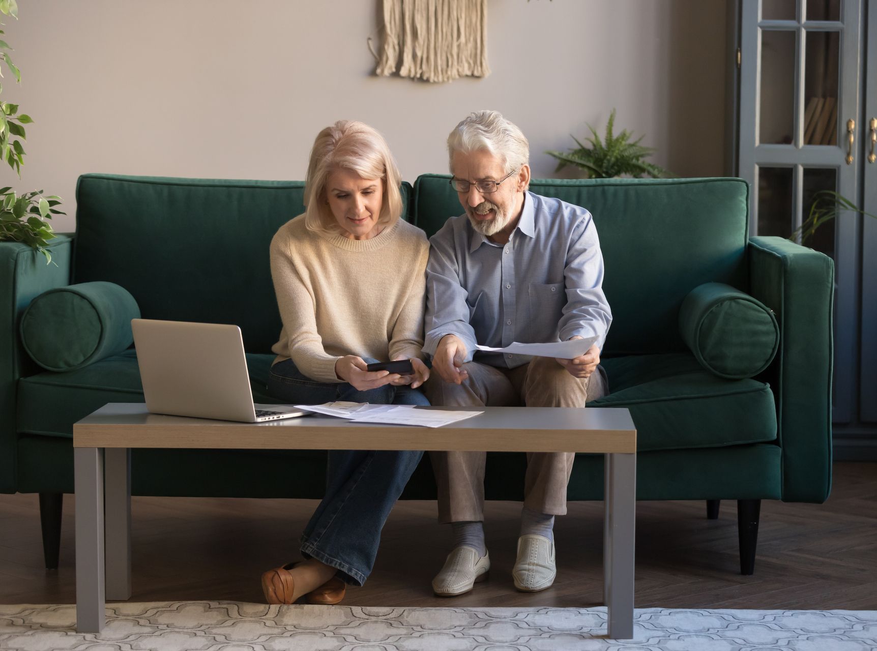 A man and a woman are sitting on a couch looking at a laptop.