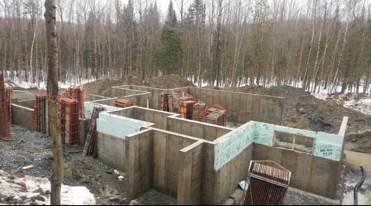 Un grand mur de béton est en construction au milieu d'une forêt.