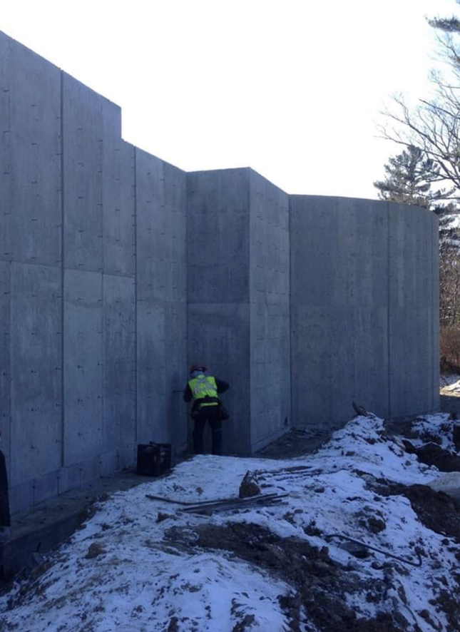 Un homme en gilet jaune se tient devant un mur de béton