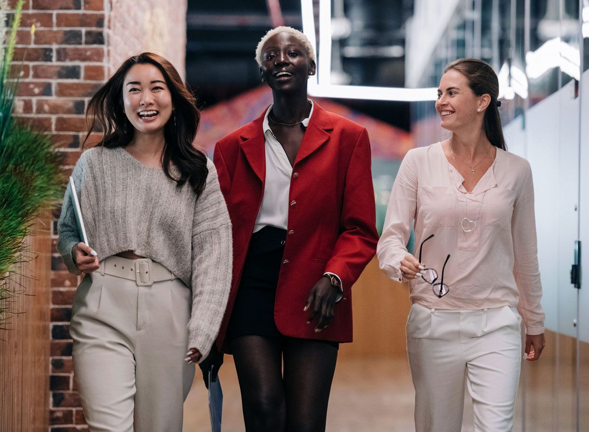 Three women are walking down a hallway together.