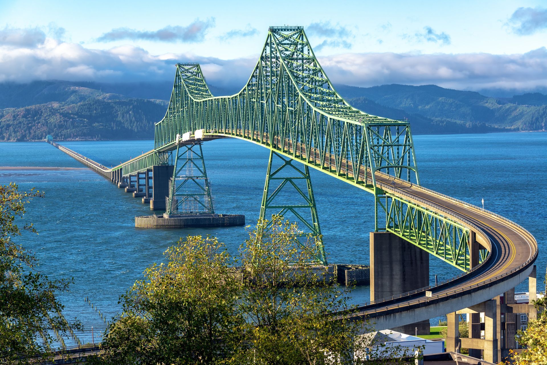 A bridge over a body of water with mountains in the background