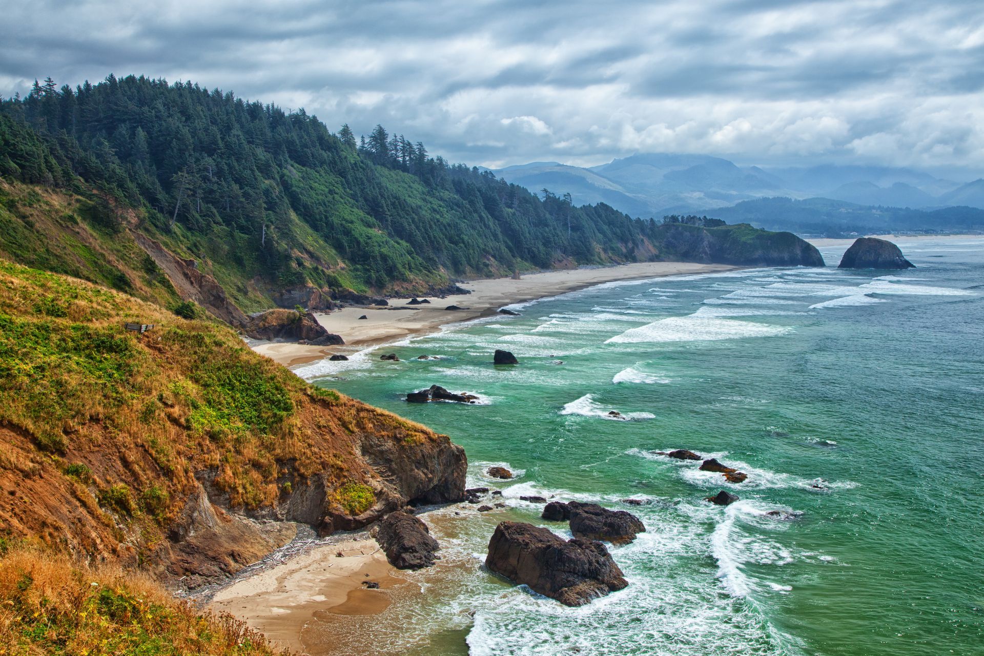 A view of a beach from a cliff overlooking the ocean.