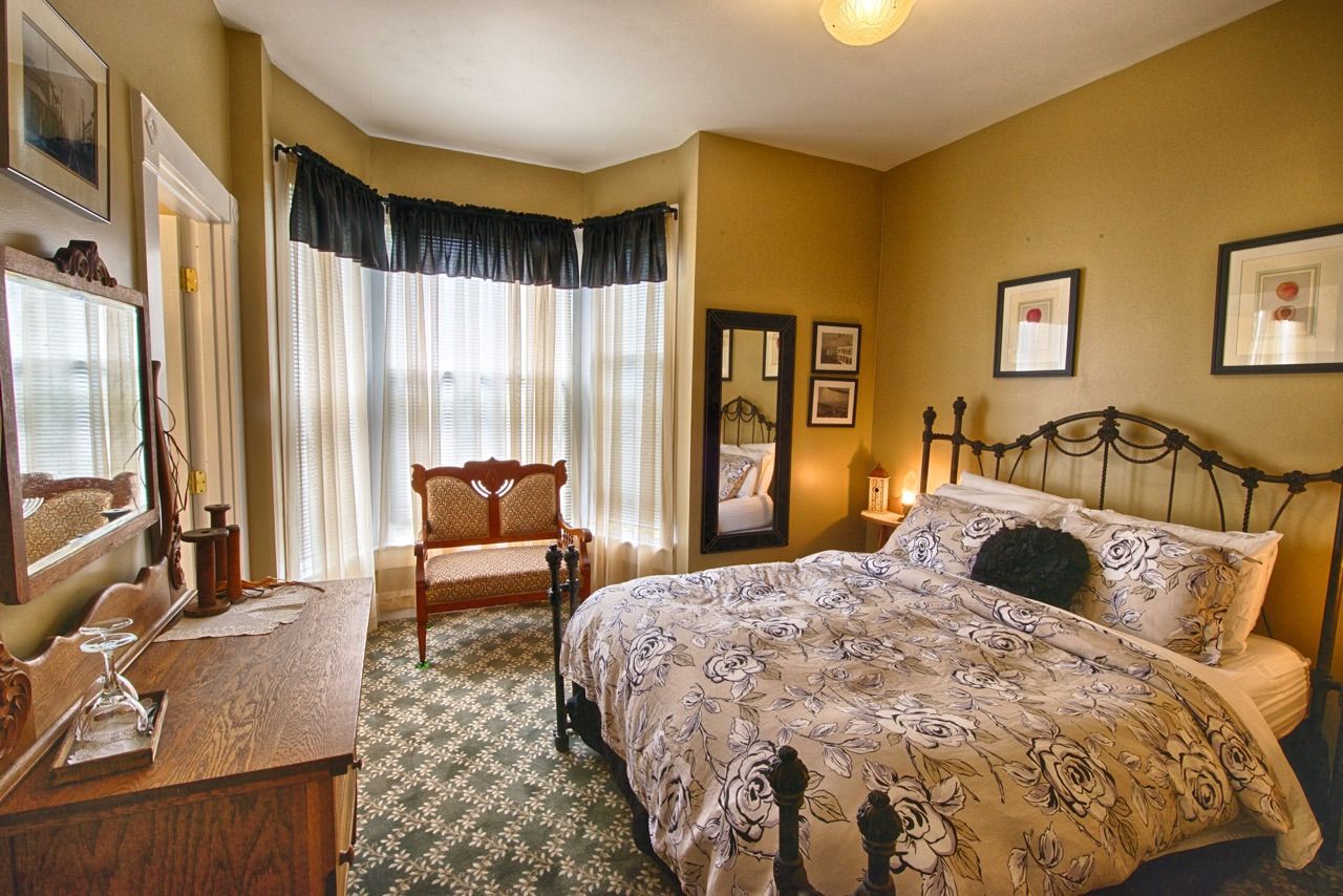 A bedroom with a king size bed , dresser , mirror and chair.