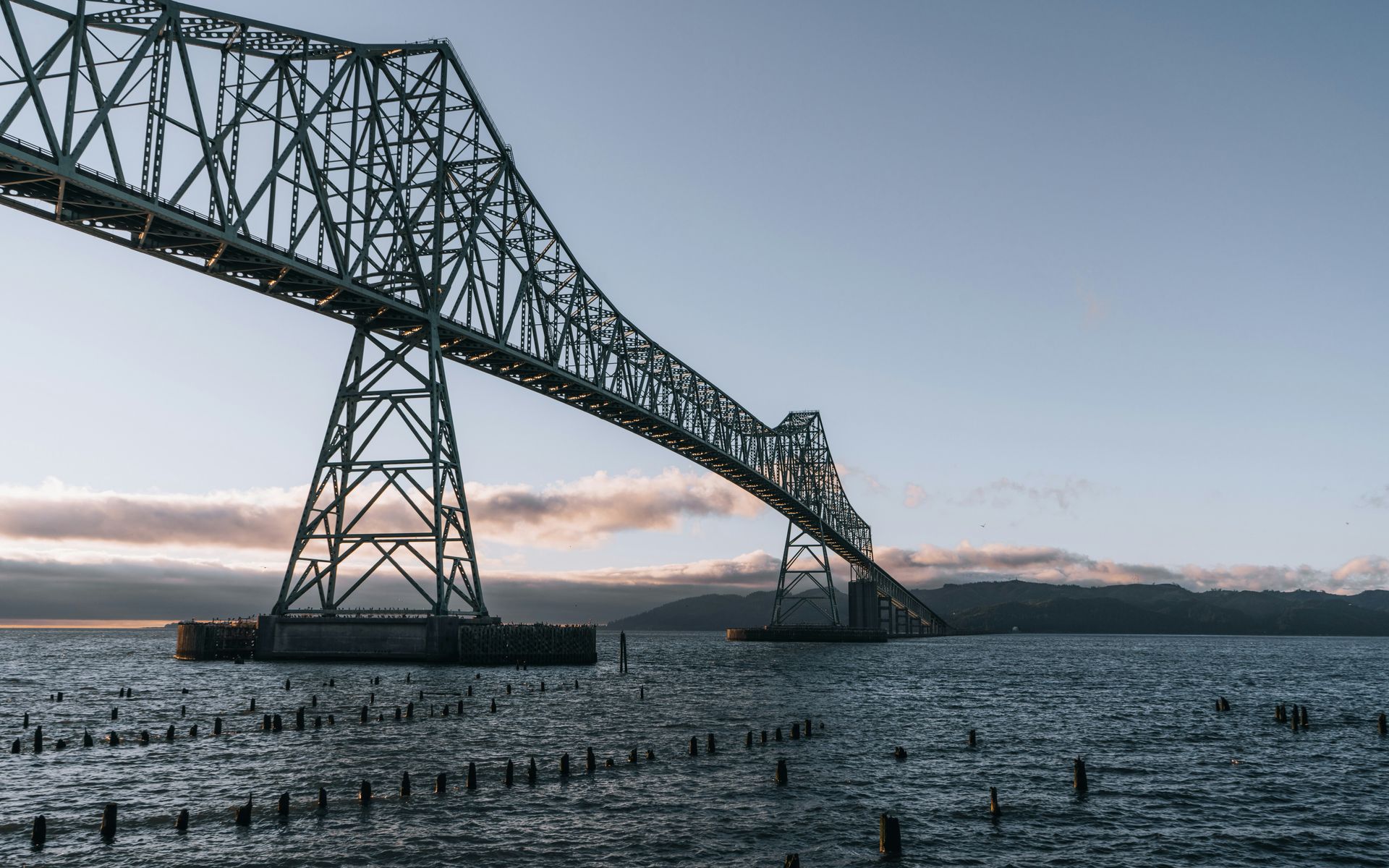 A bridge over a body of water with mountains in the background.