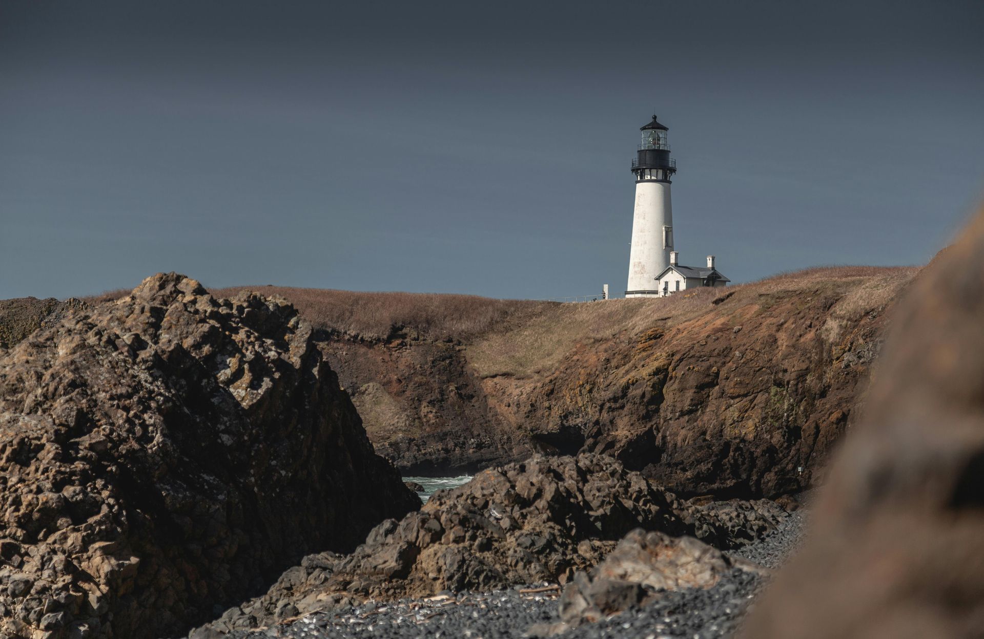 A lighthouse is sitting on top of a rocky hill.
