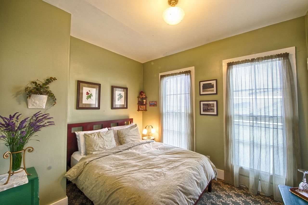 A bedroom with a bed , two windows and green walls.