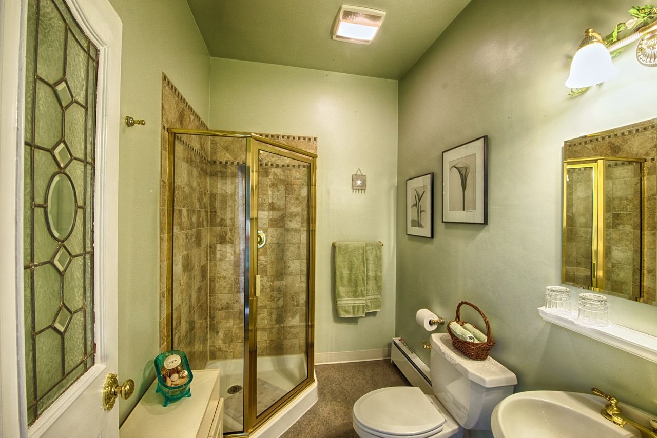 A bathroom with a toilet , sink , shower and mirror.