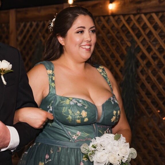 A woman in a green dress is holding a bouquet of flowers