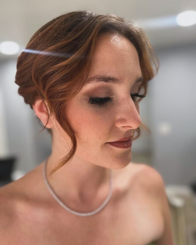 A woman with red hair is wearing a necklace and earrings.