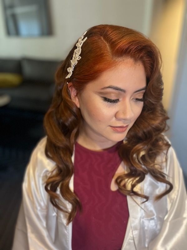 A woman with red hair is wearing a white robe and a headband.