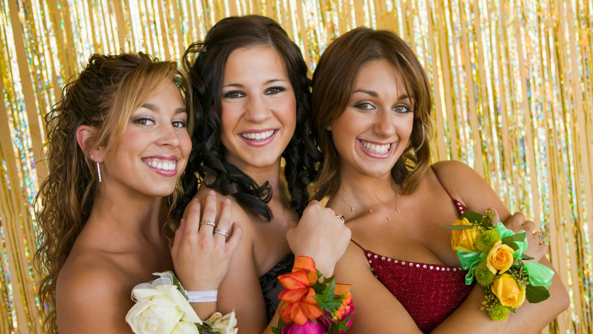 Three women in prom dresses are posing for a picture.