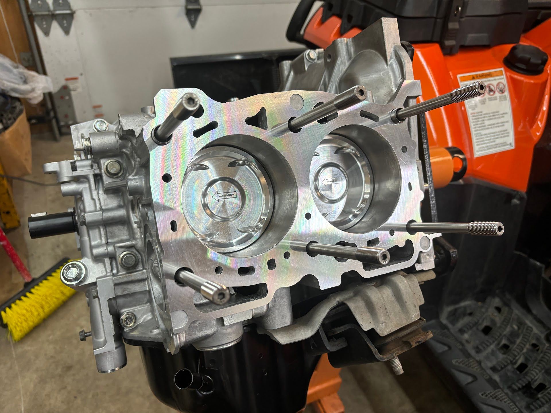 A clean, disassembled engine block with two visible pistons, sitting on a stand in a garage. | Teter Auto