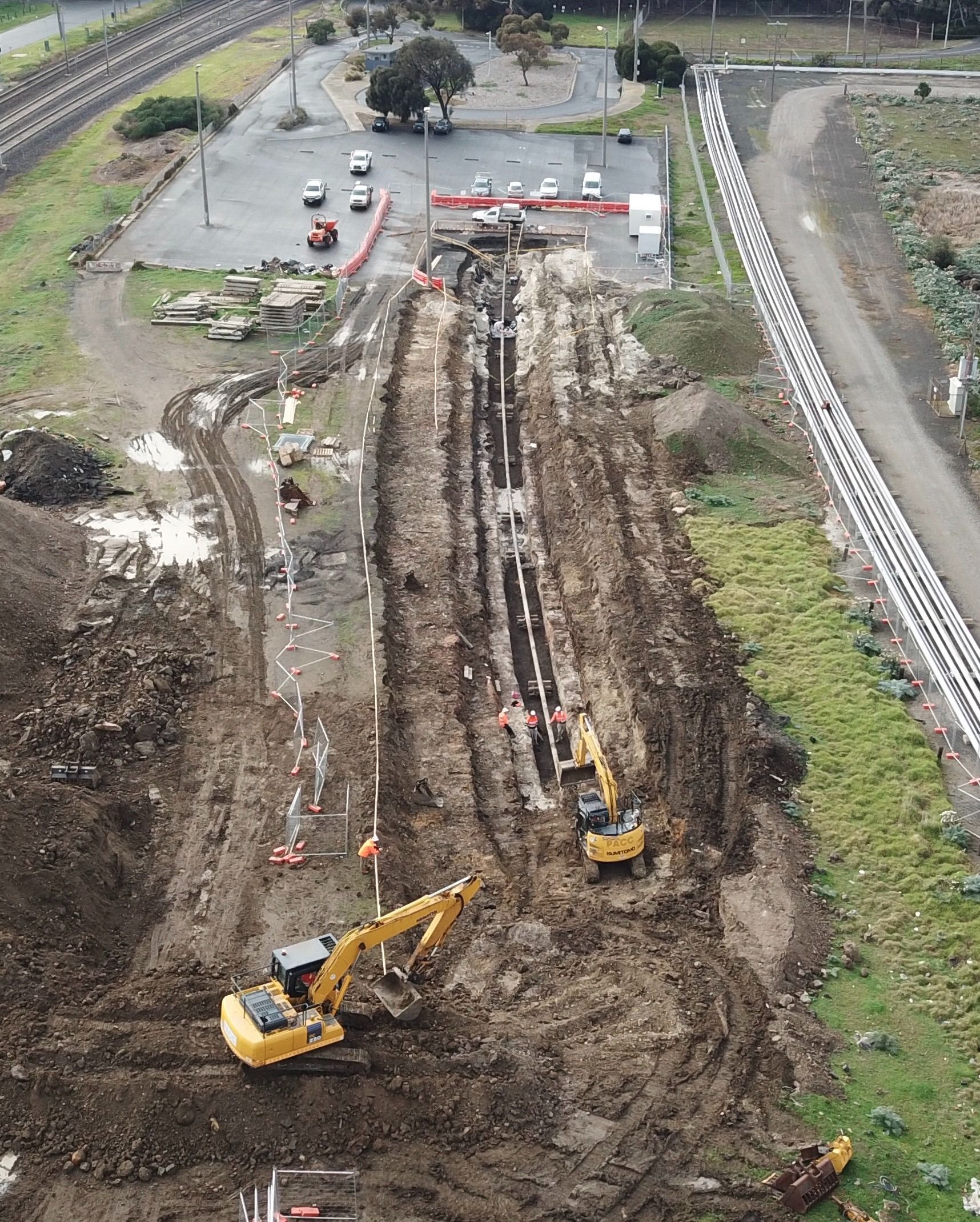 An aerial view of a construction site with a train track in the background.