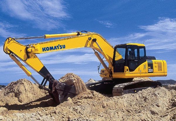 A yellow komatsu excavator is digging in the dirt
