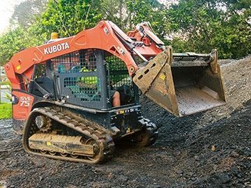 A kubota skid steer is sitting on top of a pile of dirt.