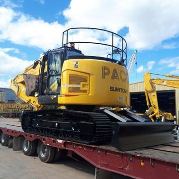 A yellow excavator is sitting on top of a red trailer.
