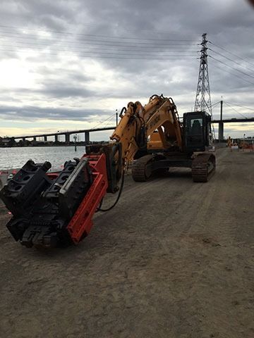 A large excavator is parked next to a large engine on a dirt road.