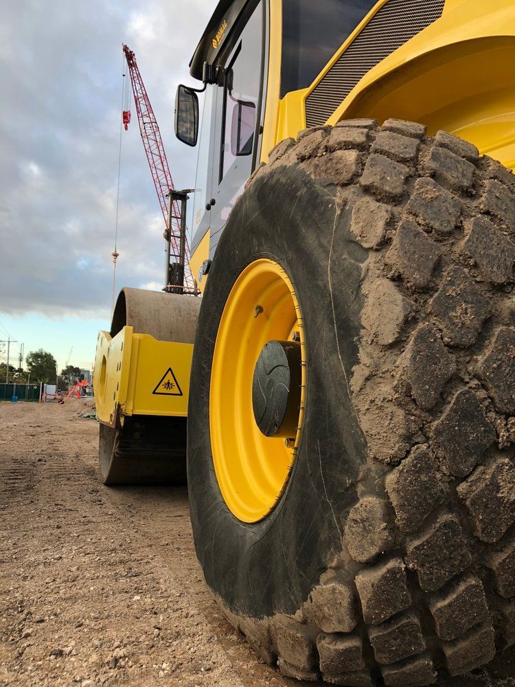 A close up of a yellow vehicle 's tire on a dirt road