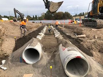 A construction site with a lot of pipes in the dirt.