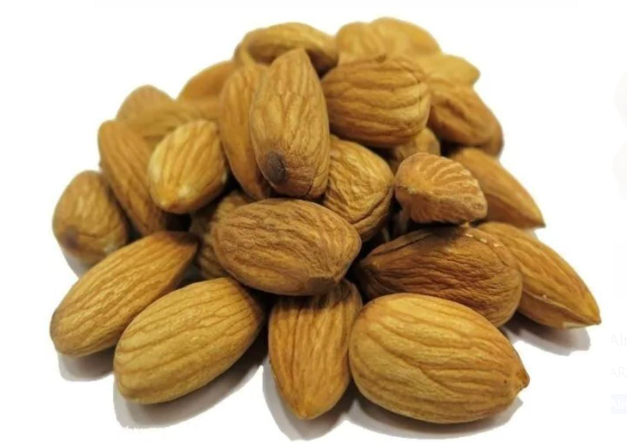 Un montón de almendras sobre una superficie blanca.