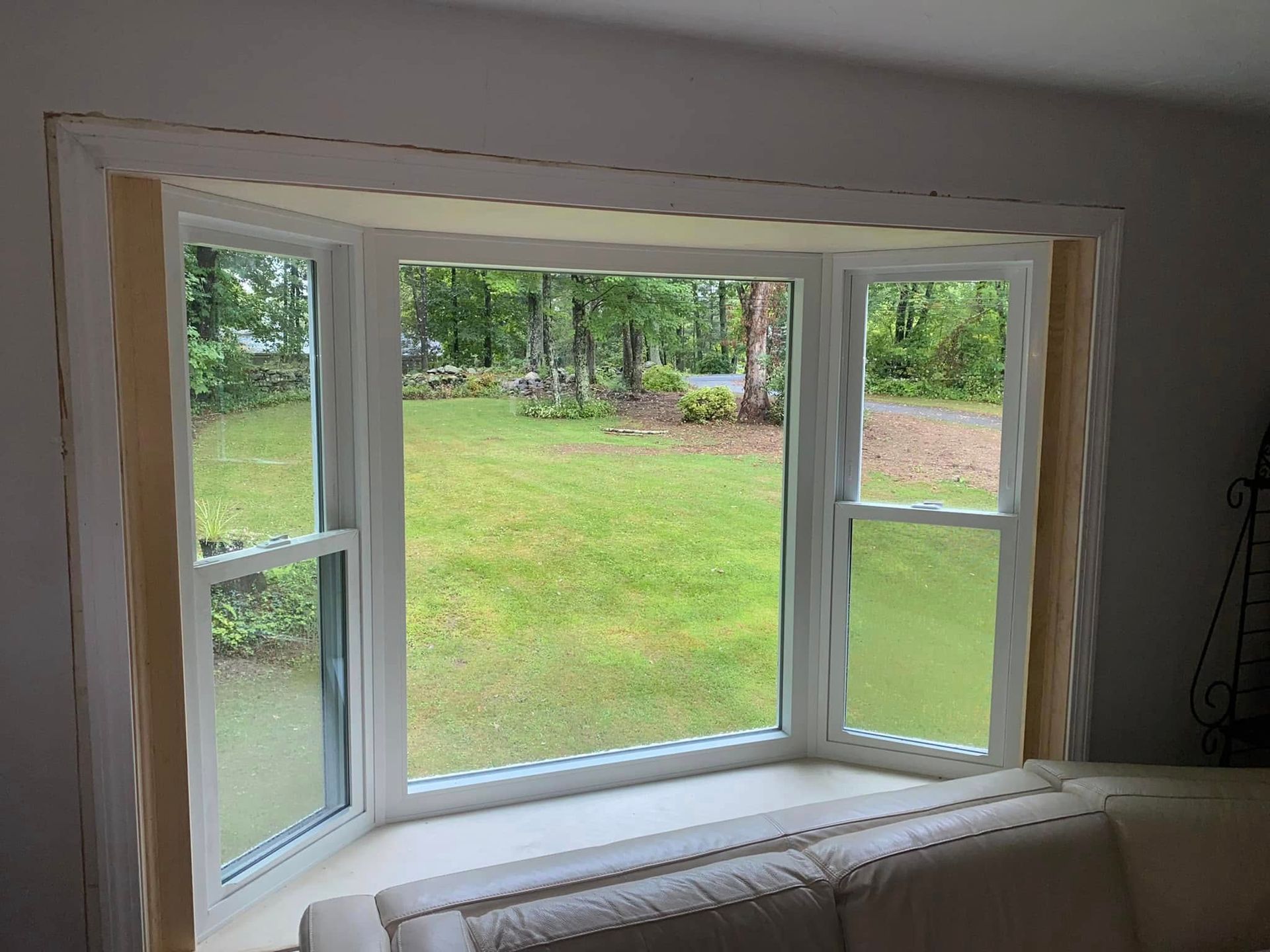 Woman in straw hat smiles, holding wine glass near a lake.