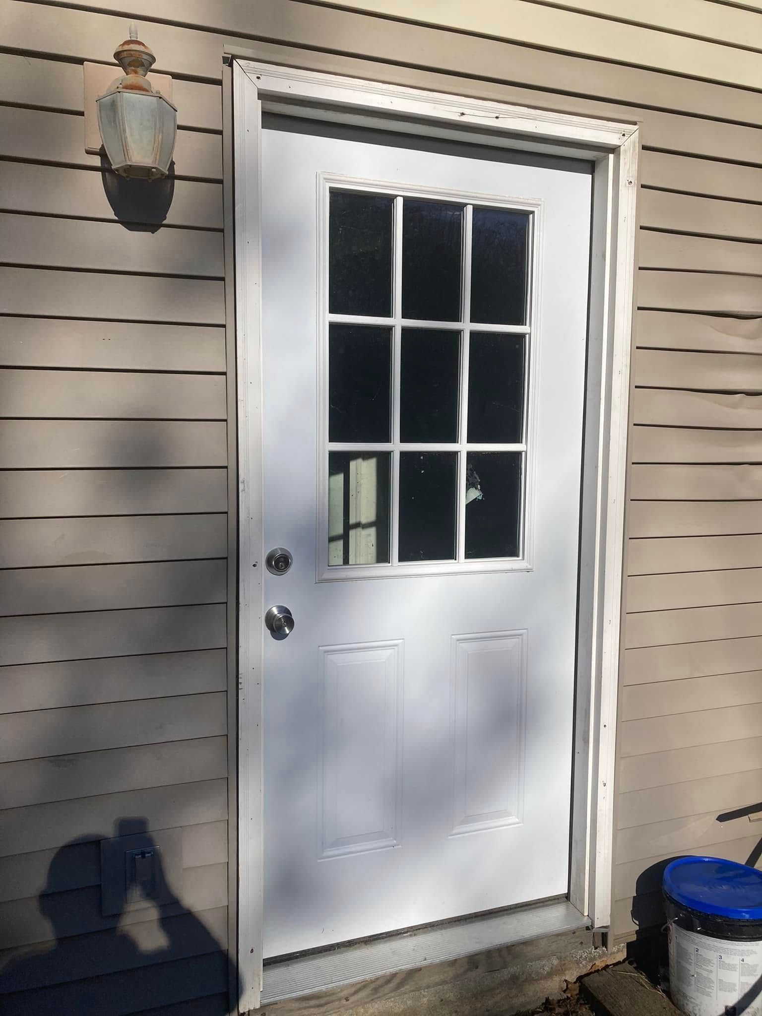 Woman in straw hat smiles, holding wine glass near a lake.