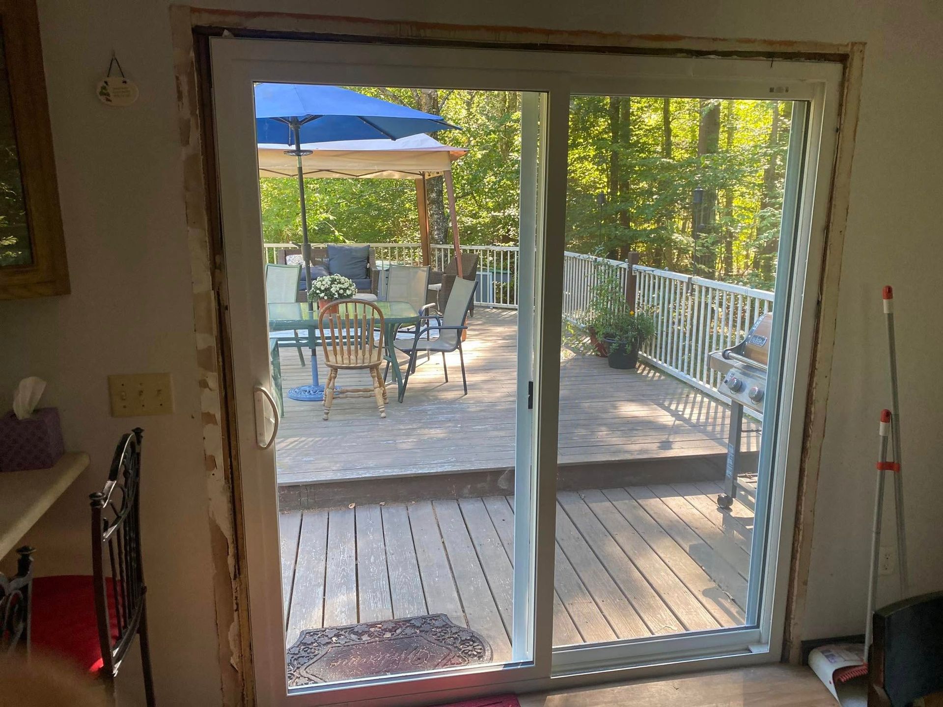 Woman in straw hat smiles, holding wine glass near a lake.