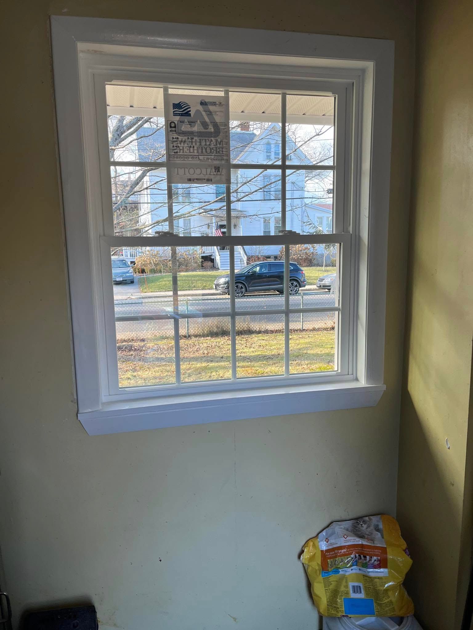 Woman in straw hat smiles, holding wine glass near a lake.