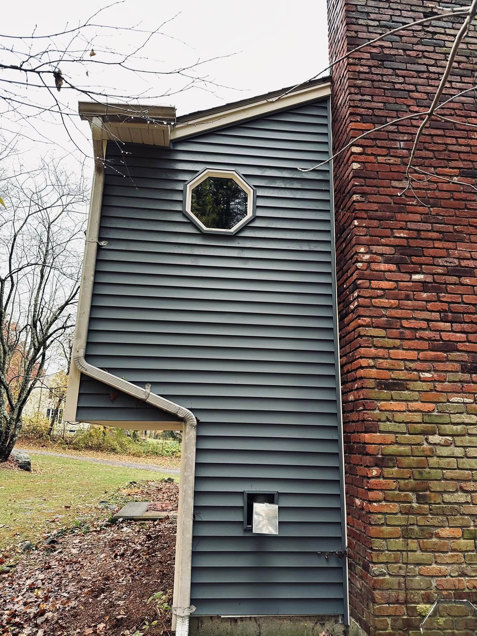 Woman in straw hat smiles, holding wine glass near a lake.