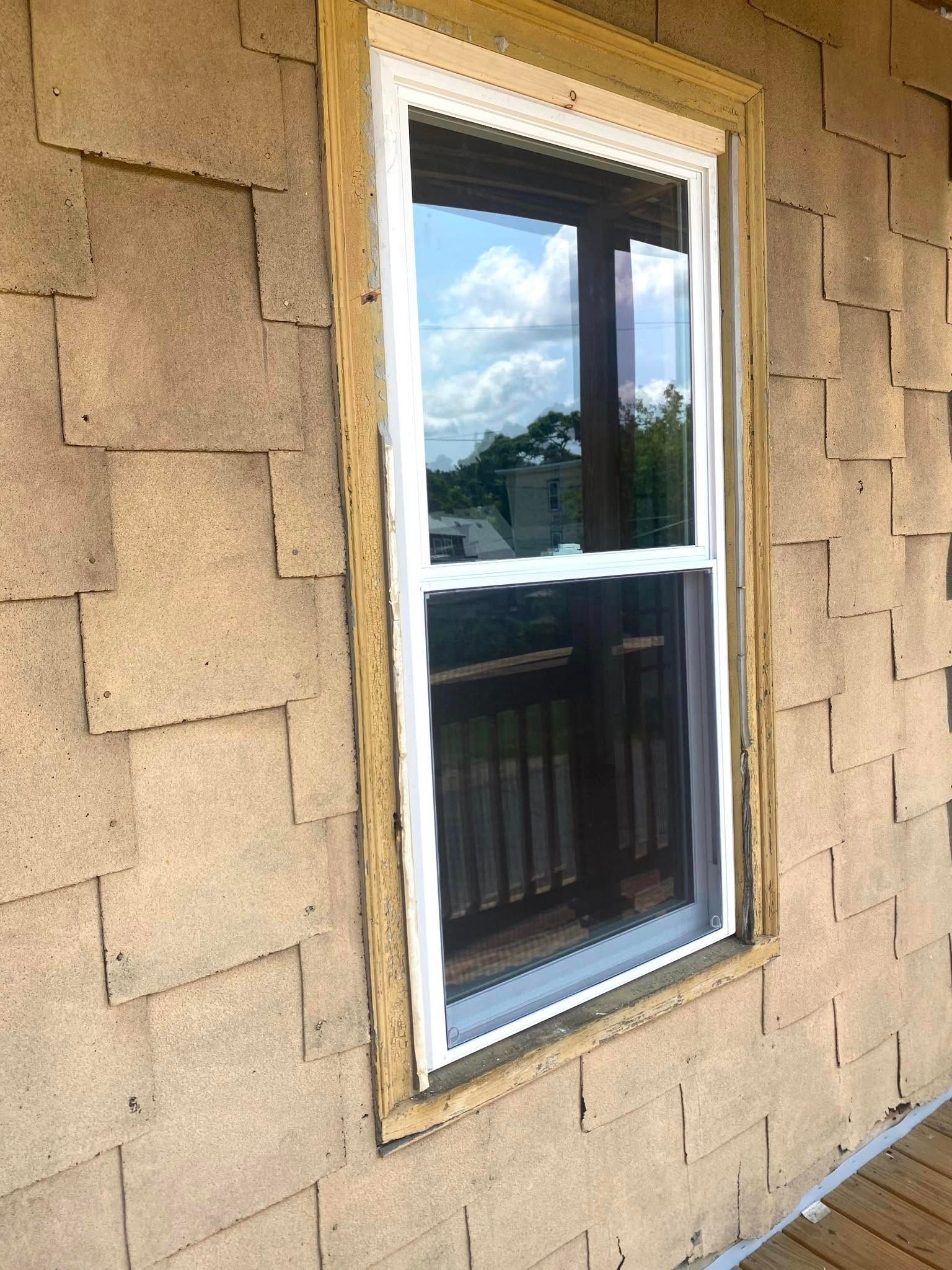 Woman in straw hat smiles, holding wine glass near a lake.